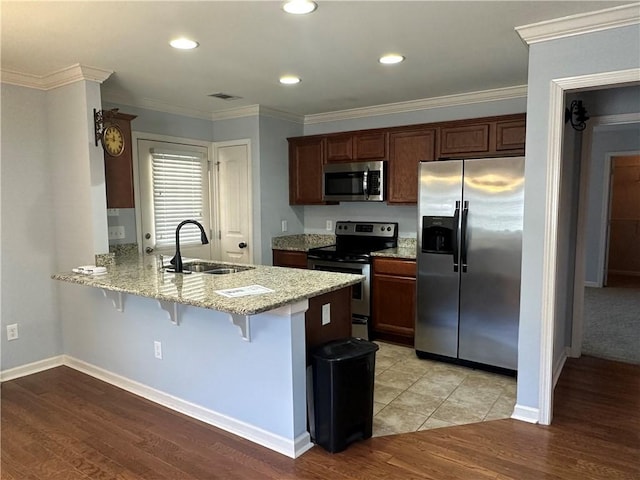 kitchen featuring stainless steel appliances, visible vents, a sink, a peninsula, and a breakfast bar area