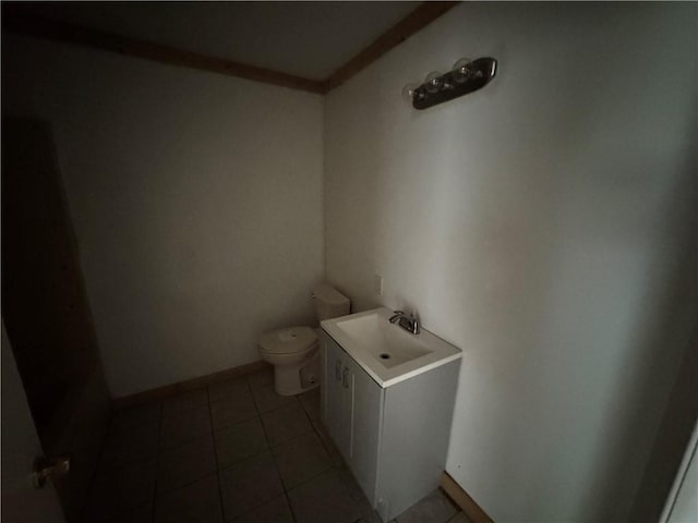 half bath with a sink, toilet, tile patterned floors, and baseboards
