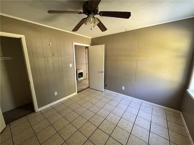 unfurnished bedroom featuring washer / dryer, light tile patterned floors, a textured ceiling, ornamental molding, and baseboards