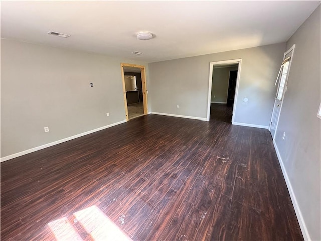 unfurnished room featuring dark wood-type flooring and baseboards