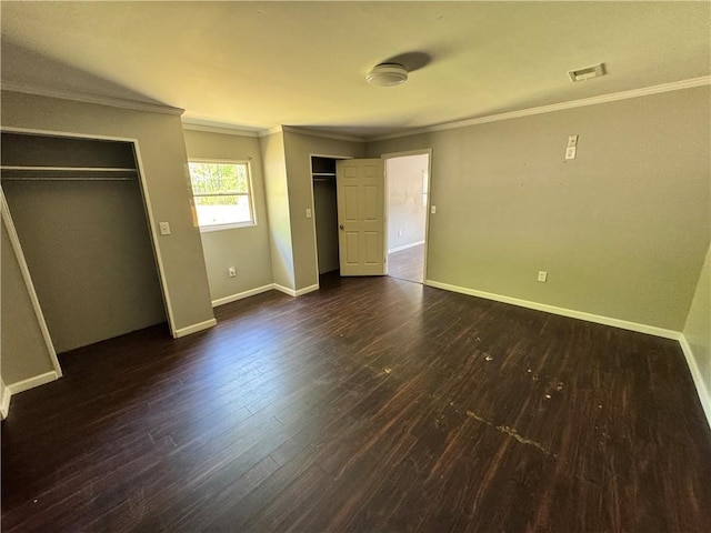 unfurnished bedroom featuring multiple closets, wood finished floors, crown molding, and baseboards