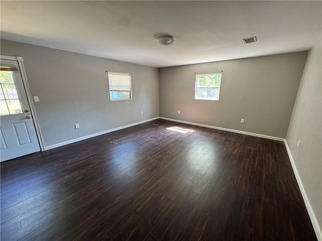 empty room featuring baseboards and dark wood-style flooring