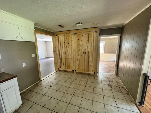 empty room featuring wood walls, a textured ceiling, baseboards, and light tile patterned flooring