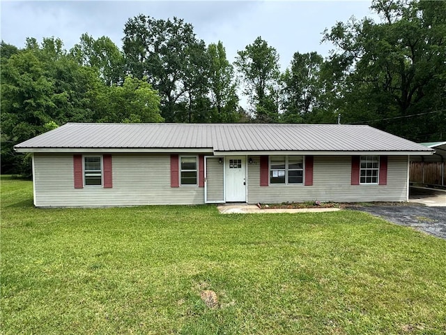 ranch-style house with a carport, metal roof, a front lawn, and driveway