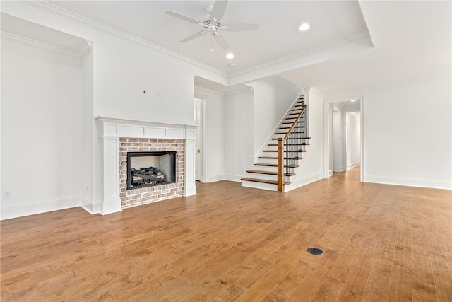 unfurnished living room featuring light hardwood / wood-style floors, a brick fireplace, ceiling fan, and ornamental molding