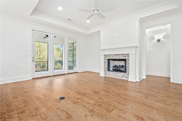 unfurnished living room featuring a fireplace, light hardwood / wood-style floors, ceiling fan, and crown molding