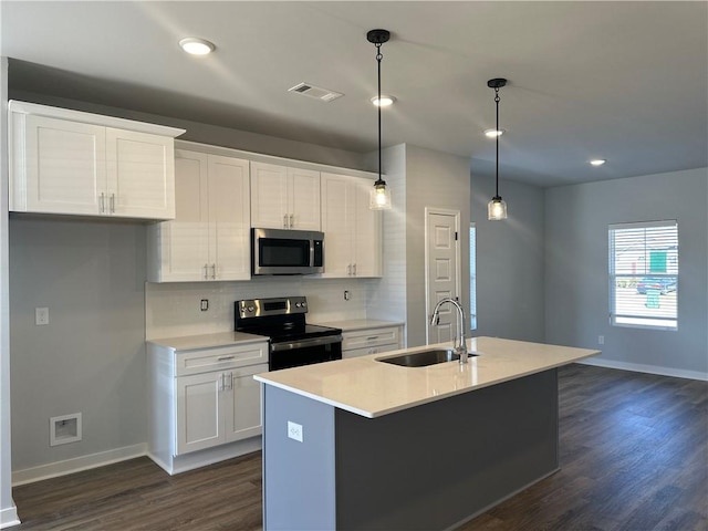 kitchen with sink, stainless steel appliances, hanging light fixtures, and an island with sink
