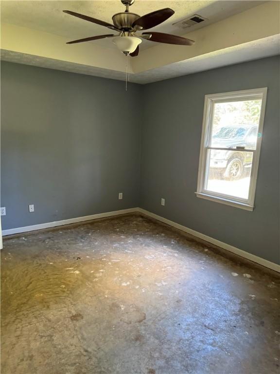 empty room featuring a tray ceiling and ceiling fan