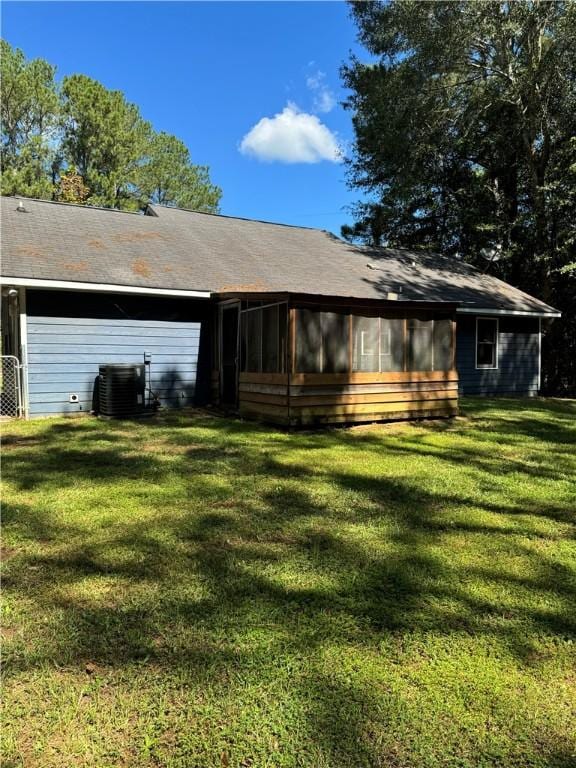 rear view of house with a sunroom, cooling unit, and a yard