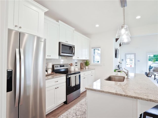 0103 Bradley Ln, Auburn, AL 36830 - kitchen featuring appliances with stainless steel finishes, a sink, an island with sink, light wood-style flooring, and white cabinets