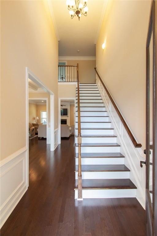 stairway with hardwood / wood-style flooring, a notable chandelier, and ornamental molding