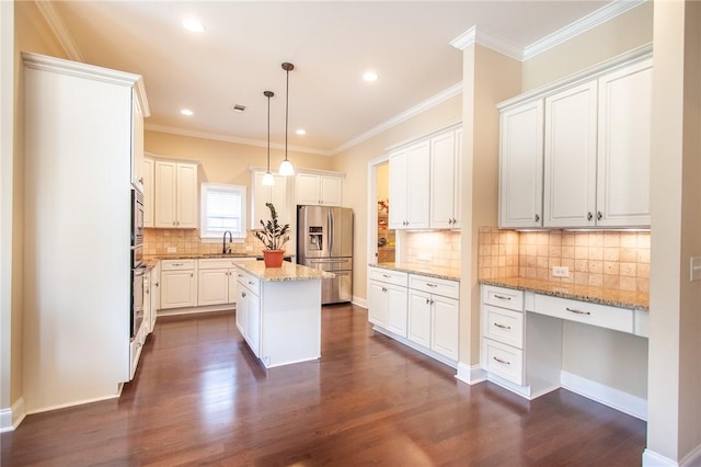 kitchen with a center island, sink, appliances with stainless steel finishes, decorative light fixtures, and light stone counters