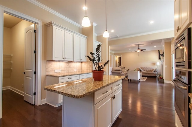 kitchen featuring pendant lighting, white cabinets, a kitchen island, light stone counters, and stainless steel appliances