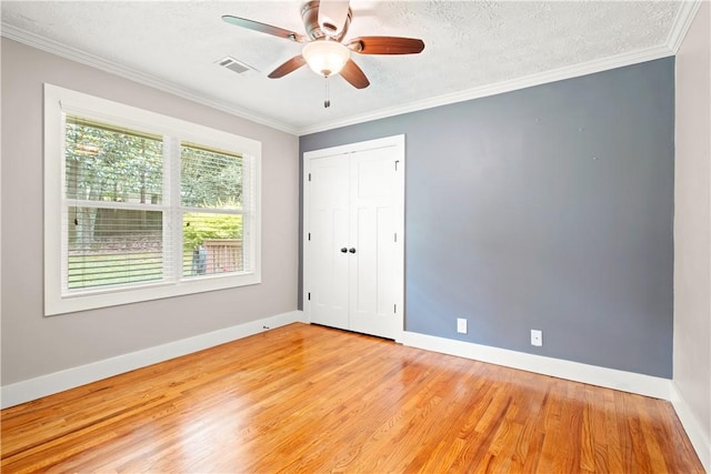 1016 E Magnolia Ave, Auburn, AL 36830 - unfurnished bedroom with light wood-style floors, crown molding, a closet, a textured ceiling, and a ceiling fan