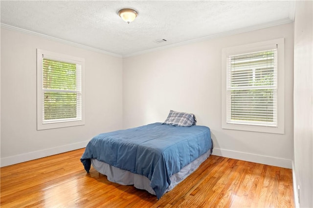 1016 E Magnolia Ave, Auburn, AL 36830 - bedroom featuring light wood-type flooring, crown molding, and a textured ceiling