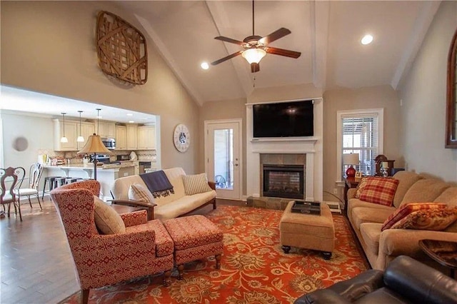 living room featuring a tile fireplace, high vaulted ceiling, and ceiling fan