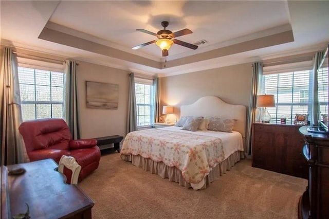 carpeted bedroom featuring a raised ceiling, ceiling fan, and ornamental molding