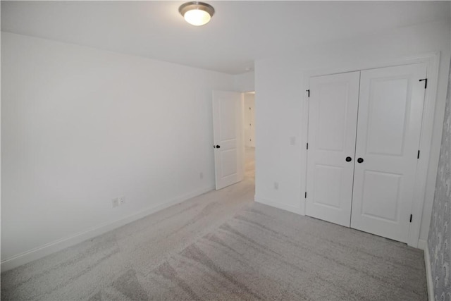 unfurnished bedroom with a closet and light colored carpet