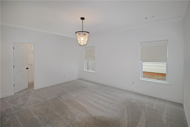 spare room featuring carpet flooring, ornamental molding, and an inviting chandelier