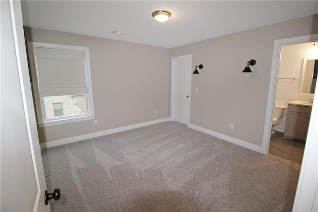 unfurnished bedroom featuring connected bathroom and carpet flooring