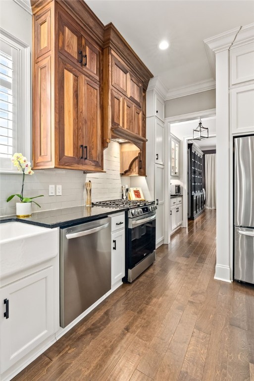 1569 Woodley Cir, Auburn, AL 36830 - kitchen featuring appliances with stainless steel finishes, dark countertops, ornamental molding, backsplash, and dark wood finished floors