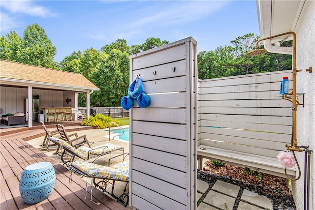 wooden terrace featuring a fenced in pool and a bar