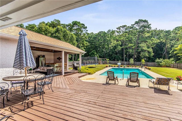 view of swimming pool featuring a yard, a deck, and a trampoline