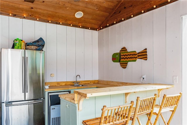 kitchen with stainless steel refrigerator, sink, wooden ceiling, wood counters, and vaulted ceiling