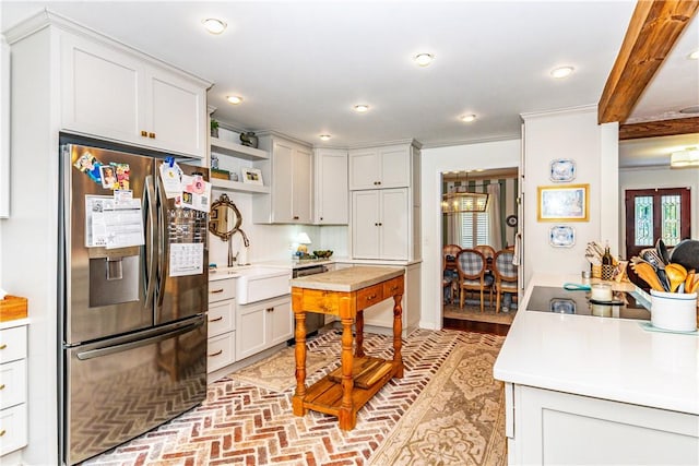 kitchen featuring stainless steel fridge, white cabinetry, sink, and ornamental molding