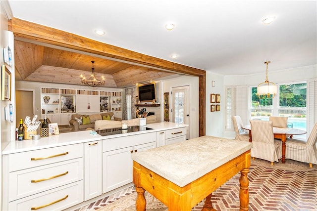 kitchen featuring a raised ceiling, a chandelier, pendant lighting, black electric stovetop, and a kitchen island