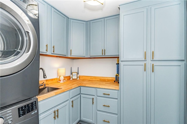 kitchen with butcher block counters, stacked washing maching and dryer, and sink