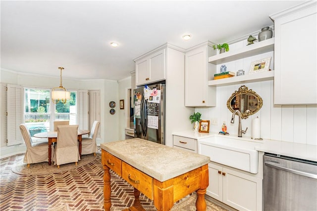 kitchen with ornamental molding, stainless steel appliances, sink, pendant lighting, and white cabinets