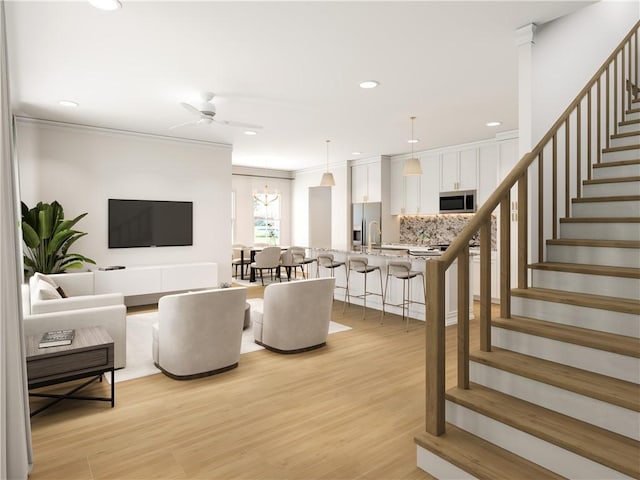 living room featuring light hardwood / wood-style floors, ornamental molding, and ceiling fan