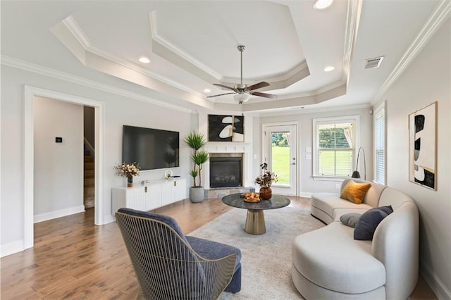 2375 Snowshill Ln, Auburn, AL 36832 - living room with a raised ceiling, ceiling fan, a glass covered fireplace, wood finished floors, and ornamental molding