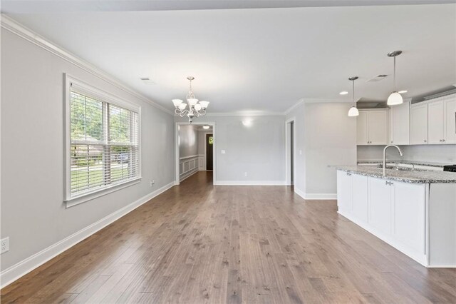 2375 Snowshill Ln, Auburn, AL 36832 - unfurnished living room with crown molding, a chandelier, light wood-style floors, a sink, and baseboards