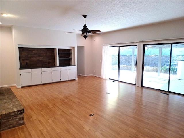 unfurnished living room with ceiling fan, a textured ceiling, and light hardwood / wood-style flooring