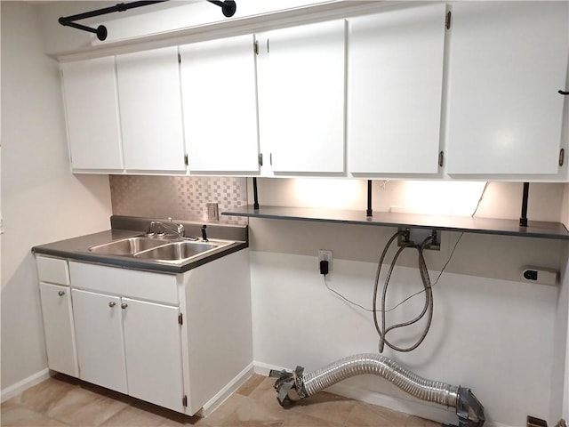 laundry area with cabinet space, electric dryer hookup, baseboards, and a sink