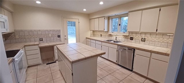 kitchen with dishwasher, white cabinets, a center island, and tile counters