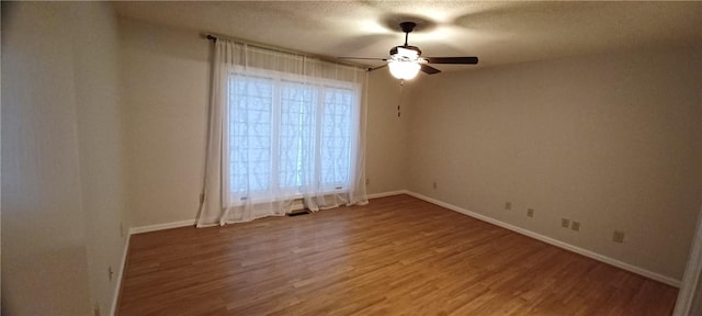 spare room featuring ceiling fan, a healthy amount of sunlight, wood-type flooring, and a textured ceiling