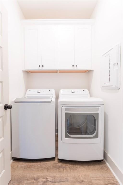 792 Village Dr, Opelika, AL 36801 - laundry room featuring washing machine and dryer, cabinet space, electric panel, and light wood-style flooring