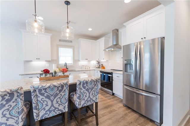 792 Village Dr, Opelika, AL 36801 - kitchen featuring appliances with stainless steel finishes, wall chimney exhaust hood, light wood-style floors, white cabinets, and recessed lighting