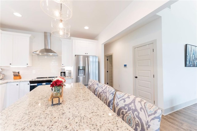 792 Village Dr, Opelika, AL 36801 - kitchen with wall chimney range hood, appliances with stainless steel finishes, light stone counters, tasteful backsplash, and recessed lighting