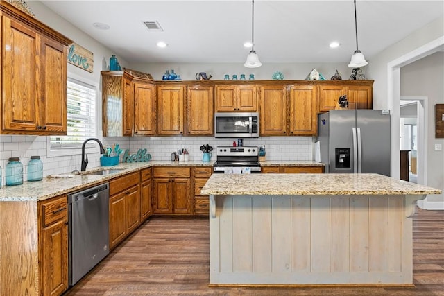 160 Indian Ln, Tallassee, AL 36078 - kitchen with stainless steel appliances, a sink, brown cabinets, a kitchen island, and wood finished floors