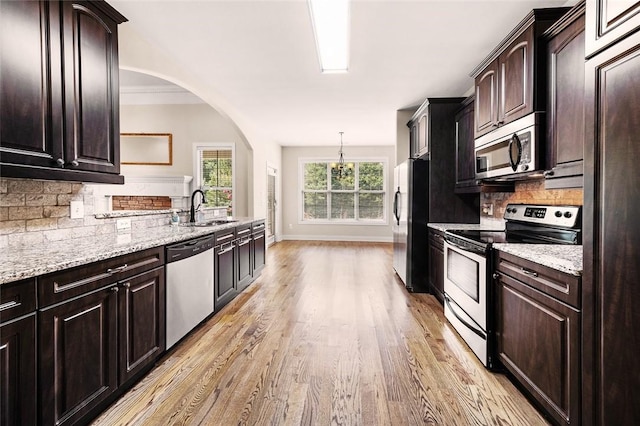 3204 Pinecrest Dr, Opelika, AL 36801 - kitchen with appliances with stainless steel finishes, light wood-style floors, backsplash, light stone counters, and arched walkways