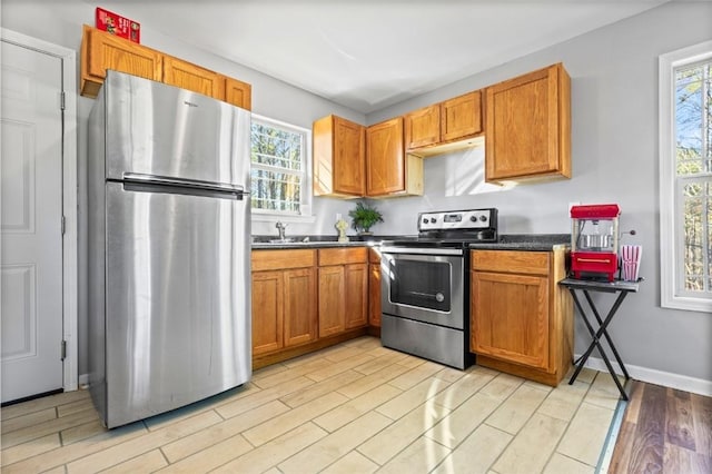 kitchen with sink, light wood-type flooring, stainless steel appliances, and a wealth of natural light