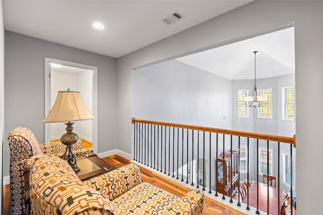 hallway with hardwood / wood-style flooring and a notable chandelier