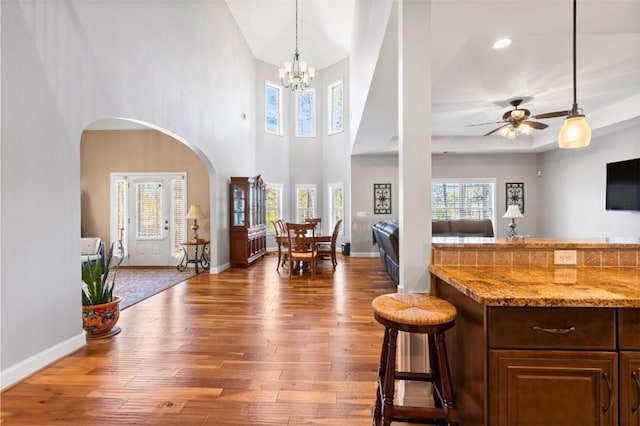 foyer entrance with a towering ceiling, wood-type flooring, and ceiling fan with notable chandelier