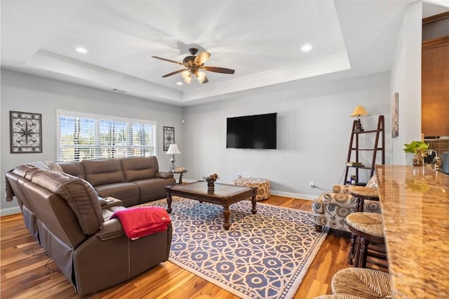 living room featuring a raised ceiling, ceiling fan, and hardwood / wood-style floors