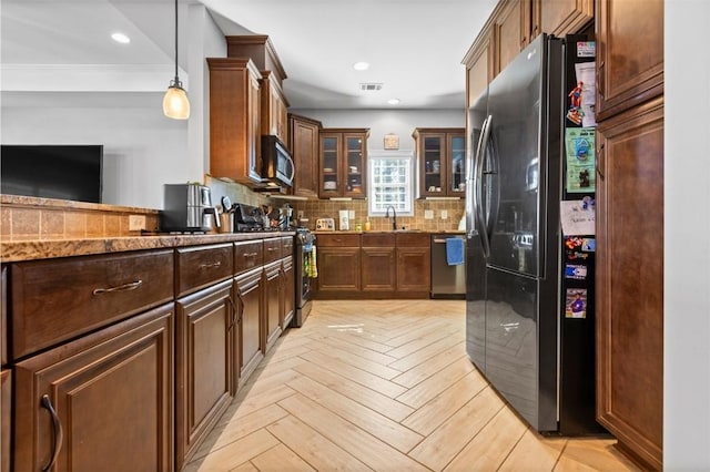 kitchen featuring pendant lighting, dark stone counters, light parquet floors, ornamental molding, and appliances with stainless steel finishes