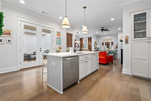 kitchen with white cabinets, ceiling fan, a center island with sink, dishwasher, and hanging light fixtures